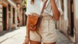 Generative AI : Street style fashion details, tanned woman wearing linen shorts, white shirt, brown leather bag and clear beige sunglasses,