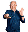© Krakenimages.com - Senior man with grey hair holding television remote control doing ok sign with fingers, smiling friendly gesturing excellent symbol