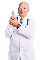 Wall Mural - Senior handsome grey-haired man wearing doctor coat and stethoscope holding symbolic gun with hand gesture, playing killing shooting weapons, angry face