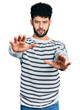 © Krakenimages.com - Young arab man with beard wearing casual striped sweater doing stop gesture with hands palms, angry and frustration expression