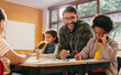 Primary educator smiling at the camera in a classroom. Teacher teaching a group of children in a school