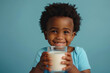 Happy African American little boy with glass of milk isolated on blue background