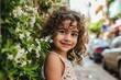 Portrait of a beautiful little girl with curly hair in a summer dress on the street