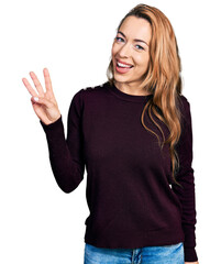 Wall Mural - Young caucasian woman wearing casual clothes showing and pointing up with fingers number three while smiling confident and happy.