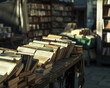 A table full of books is in front of a building. The books are arranged in stacks and are of various sizes. The scene gives off a feeling of a library or a bookstore