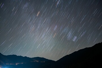 Long exposure shot of a starry sky over silhouettes of mountains