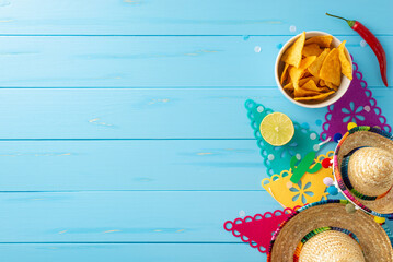 Wall Mural - Cinco de Mayo celebration essentials. Top view of traditional props: sombreros, flag garland, lime, chilli, and nachos arranged on wooden blue backdrop. Perfect for festive advertising