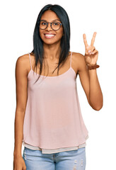 Wall Mural - Young african american woman wearing casual clothes and glasses showing and pointing up with fingers number two while smiling confident and happy.