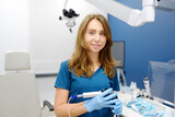 Fototapeta Tulipany - Portrait of female ENT doctor with endoscope in her hands during appointment of patient in medical office. Professional otolaryngologist is on workplace. Beautiful woman looking at camera