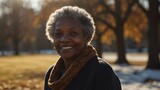 Fototapeta  - elderly black african lady woman on morning sunlight winter park background smiling happy looking at camera with copy space for banner backdrop from Generative AI
