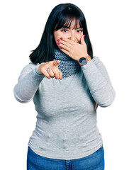 Poster - Young hispanic plus size woman wearing winter scarf laughing at you, pointing finger to the camera with hand over mouth, shame expression