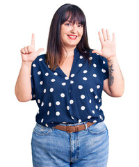 Canvas Print - Young plus size woman wearing casual clothes showing and pointing up with fingers number seven while smiling confident and happy.