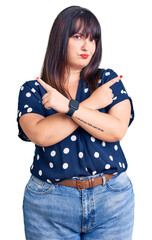 Poster - Young plus size woman wearing casual clothes pointing to both sides with fingers, different direction disagree