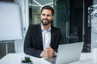© Ivan - portrait of a happy bearded handsome man at workplace at computer desk in office. Business male employee entrepreneur or manager sitting at work look pensive