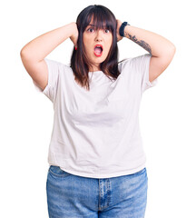 Canvas Print - Young plus size woman wearing casual clothes crazy and scared with hands on head, afraid and surprised of shock with open mouth