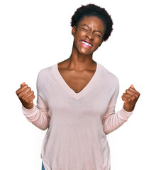 Wall Mural - Young african american girl wearing casual clothes very happy and excited doing winner gesture with arms raised, smiling and screaming for success. celebration concept.