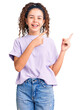 © Krakenimages.com - Beautiful kid girl with curly hair wearing casual clothes smiling and looking at the camera pointing with two hands and fingers to the side.