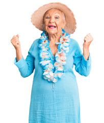 Wall Mural - Senior beautiful woman with blue eyes and grey hair wearing summer hat and hawaiian lei screaming proud, celebrating victory and success very excited with raised arms