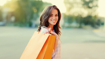 Wall Mural - happy brunette young woman with shopping bags walking in the city