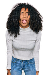 Wall Mural - Young african american girl wearing casual clothes sticking tongue out happy with funny expression. emotion concept.