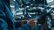 © Zaleman - The car service manager or mechanic uses a tablet computer equipped with a futuristic interactive diagnostics software so that they can inspect the vehicle for broken components in the engine bay...