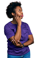 Sticker - African american woman with afro hair wearing casual purple t shirt with hand on chin thinking about question, pensive expression. smiling with thoughtful face. doubt concept.