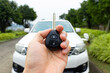 Car key in hand with car on the background. Car stuff concept.