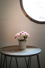 Wall Mural - An artificial rose flower pot in placed on the wooden table for interior decoration. Close-up and selective focus.