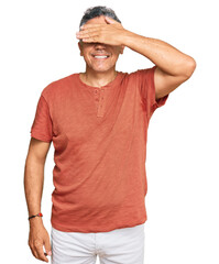 Canvas Print - Handsome middle age man wearing casual clothes smiling and laughing with hand on face covering eyes for surprise. blind concept.