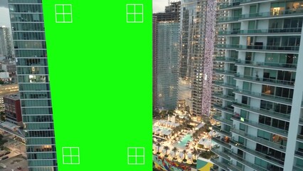 Empty billboard green screen on skyscraper building for advertising with tracking markers. Miami modern urban cityscape, aerial