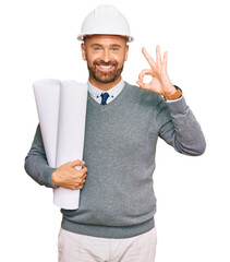 Poster - Handsome middle age man holding paper blueprints doing ok sign with fingers, smiling friendly gesturing excellent symbol