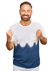 Poster - Handsome middle age man wearing casual tie dye tshirt very happy and excited doing winner gesture with arms raised, smiling and screaming for success. celebration concept.