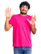 © Krakenimages.com - Handsome young man with curly hair and bear wearing casual pink tshirt afraid and terrified with fear expression stop gesture with hands, shouting in shock. panic concept.