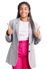 Poster - Young african american woman with braids wearing business clothes success sign doing positive gesture with hand, thumbs up smiling and happy. cheerful expression and winner gesture.