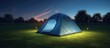 Outdoor camping tent with tarp or flysheet on grass courtyard and warm night light under dark blue sky twilight time