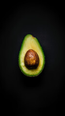 Half of a ripe avocado with seed on dark background