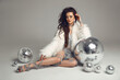 Disco girl. Glamorous brunette in sexy dress with white fur coat over disco glass balls. New Year party. Nightclub. Beautiful lady posing long legs isolated