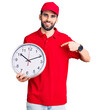 © Krakenimages.com - Young handsome man with beard wearing delivery uniform holding big clock pointing finger to one self smiling happy and proud