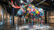 A large, colorful sculpture of a moose made from recycled materials. The sculpture is on display in a large, empty room with a lot of white walls. Scene is one of creativity