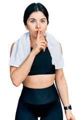 Poster - Young brunette woman with blue eyes wearing sportswear and towel asking to be quiet with finger on lips. silence and secret concept.