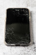 Modern mobile phone with broken screen on stone background.