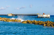 View of the Caribbean Sea with a pier and an artificial breakwater where waves crash against the rocks. Curacao.