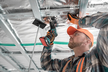 Plasterboard worker making a plasterboard ceiling. Assembling the support structure from CD profiles for plasterboard.