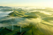 Misty Morning Over Green Hills with Wind Turbines