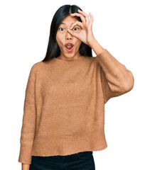 Sticker - Beautiful young asian woman wearing casual winter sweater doing ok gesture shocked with surprised face, eye looking through fingers. unbelieving expression.