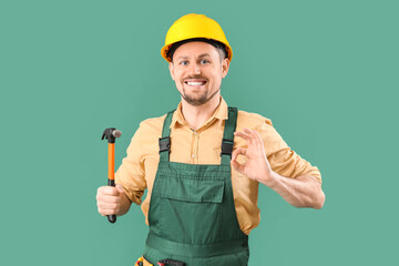 Canvas Print - Male carpenter with hammer showing OK on green background