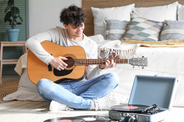 Poster - Young man with record player playing guitar in bedroom