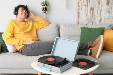 Wall Mural - Young man in headphones with record player at home