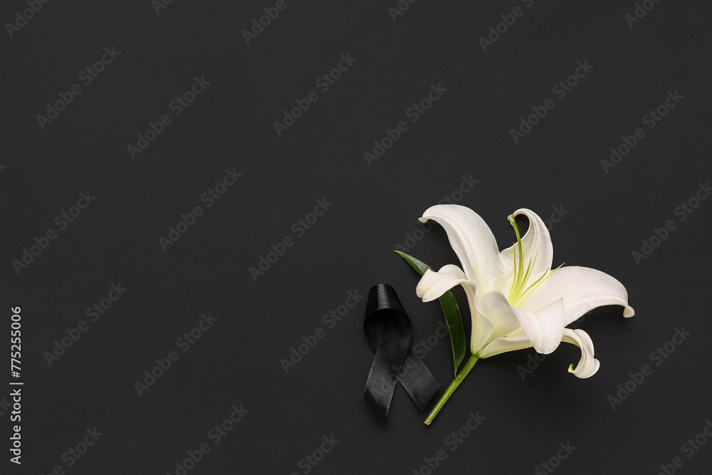 Beautiful lily flower with black funeral ribbon on dark background