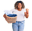 Young african american plus size woman holding laundry basket annoyed and frustrated shouting with anger, yelling crazy with anger and hand raised